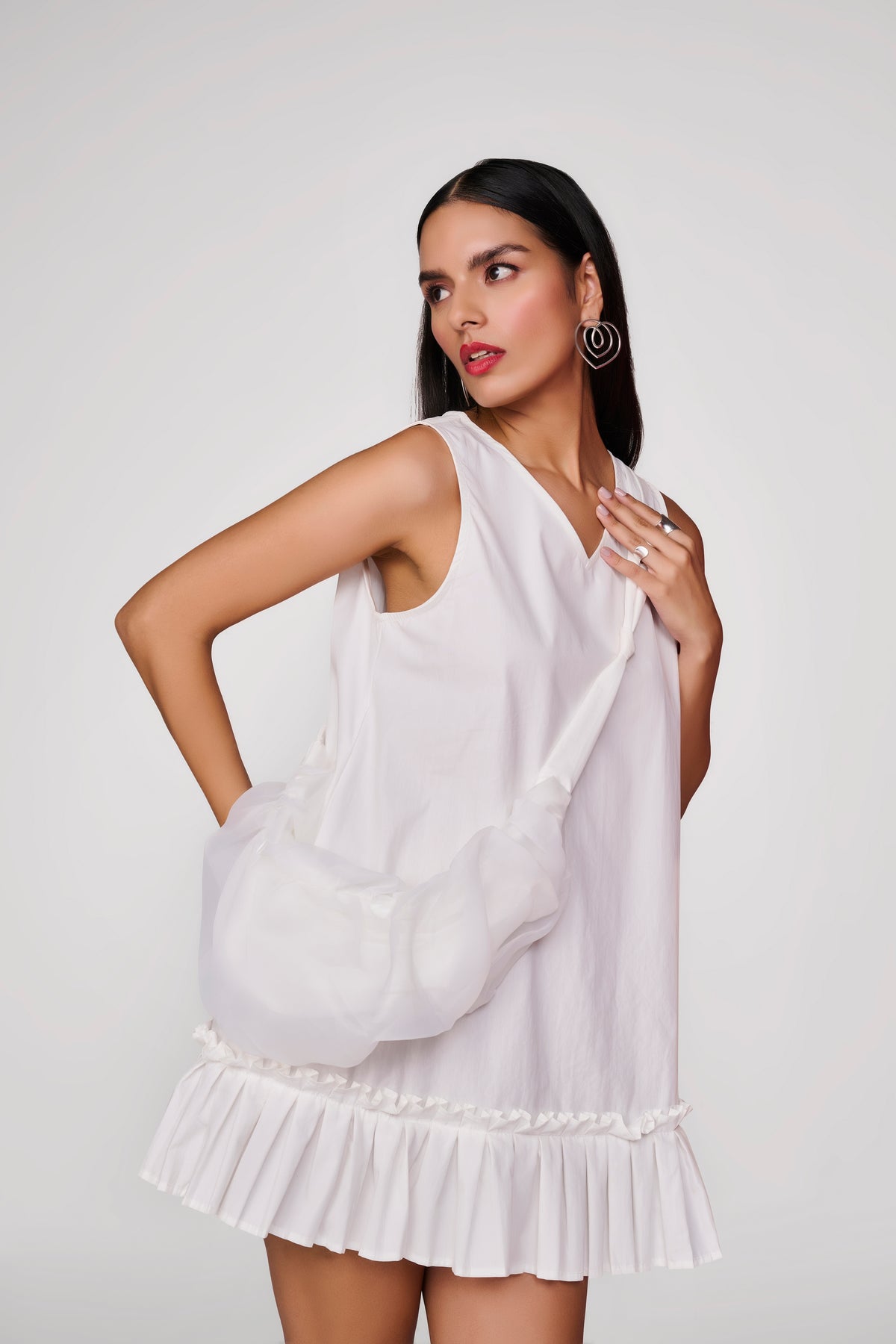 Short white dress with pleated detail at hem and sling bag