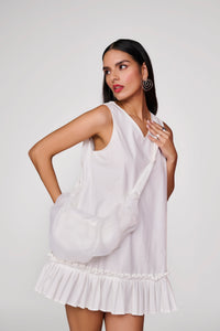 Short white dress with pleated detail at hem and sling bag