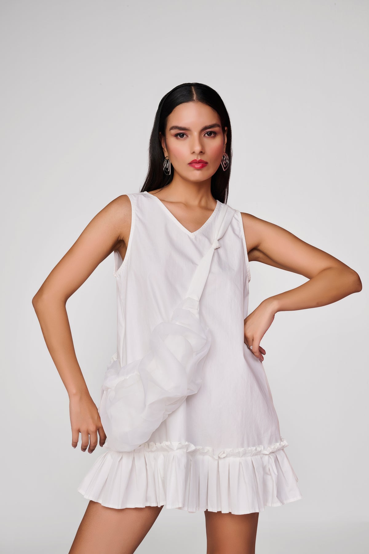 Short white dress with pleated detail at hem and sling bag
